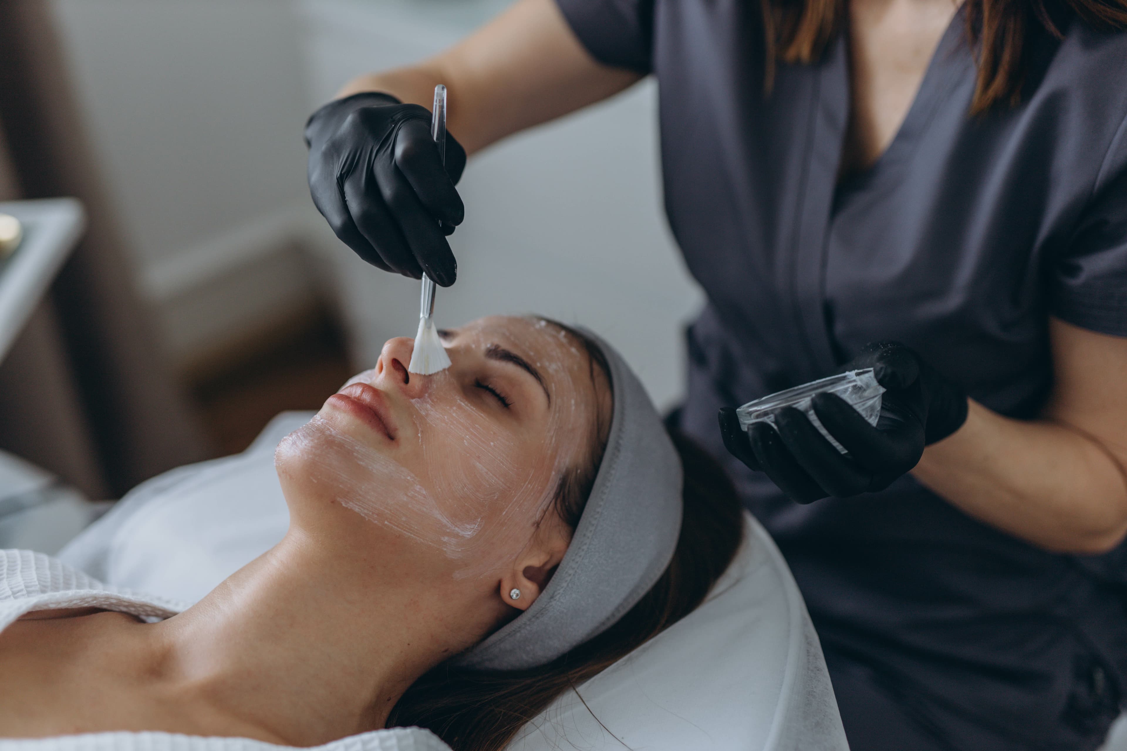 An esthetician applying a chemical peel during a facial