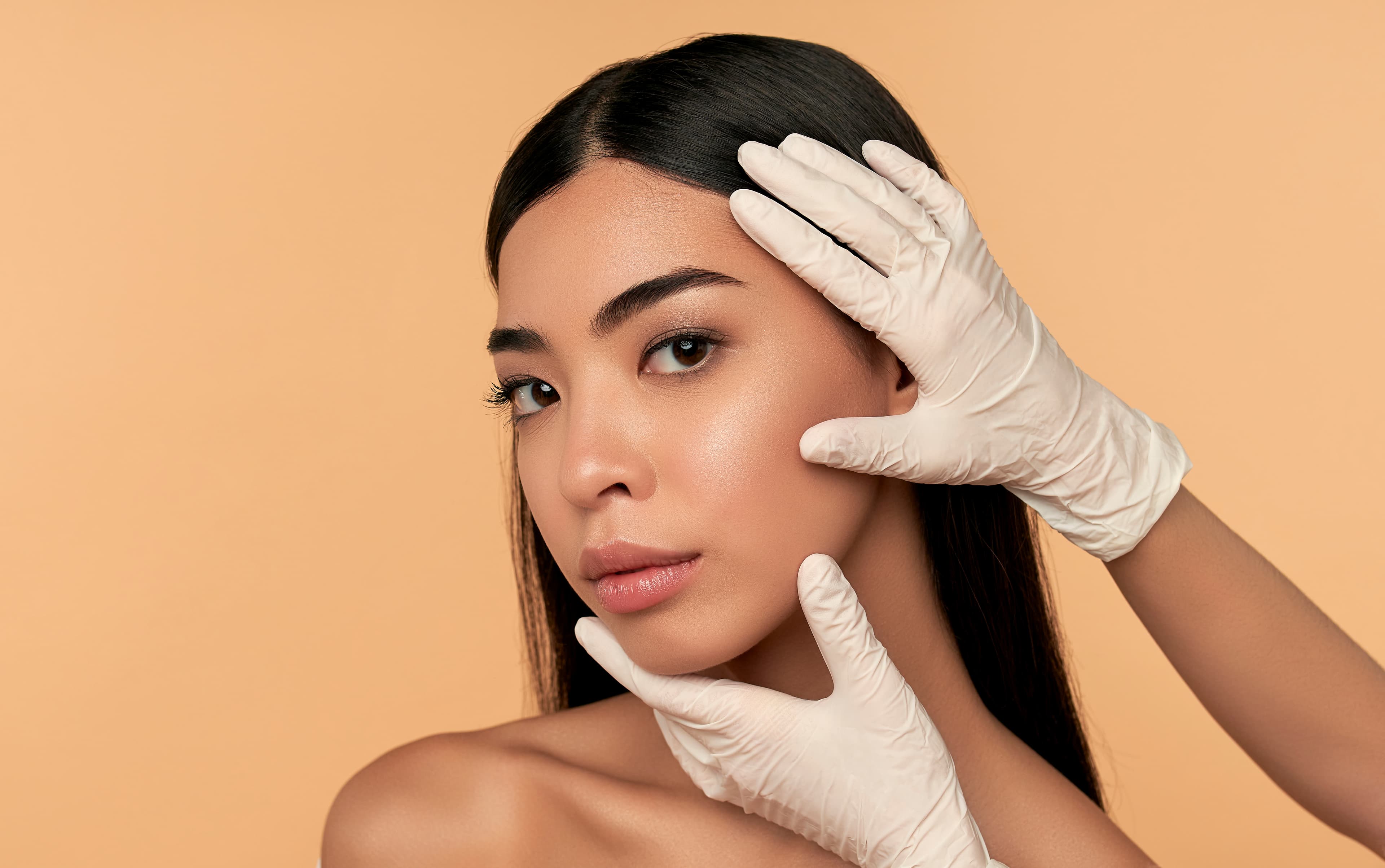 A provider assessing a patient's face before an injectable treatment